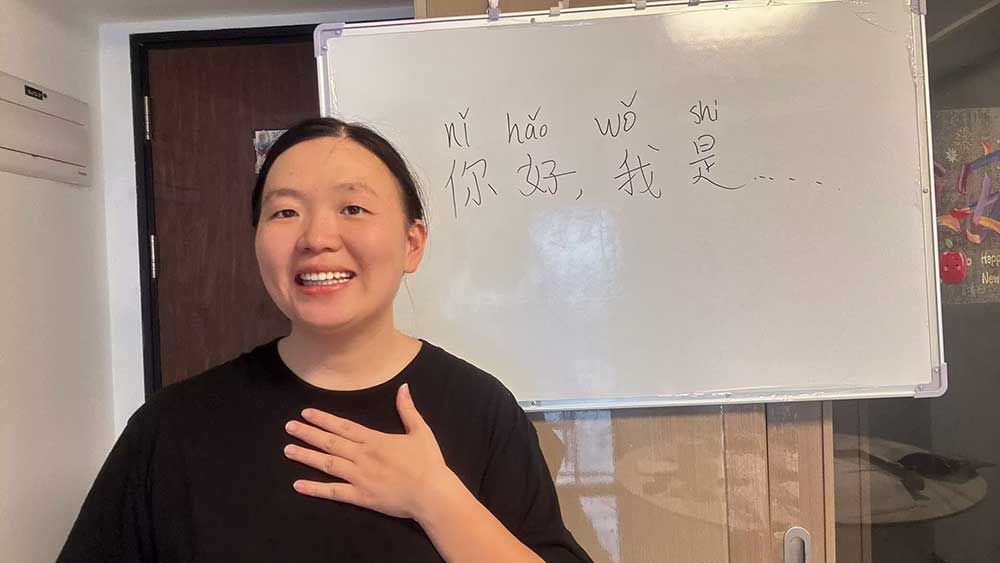 Mandarin tutor Candice teaching greetings at the whiteboard